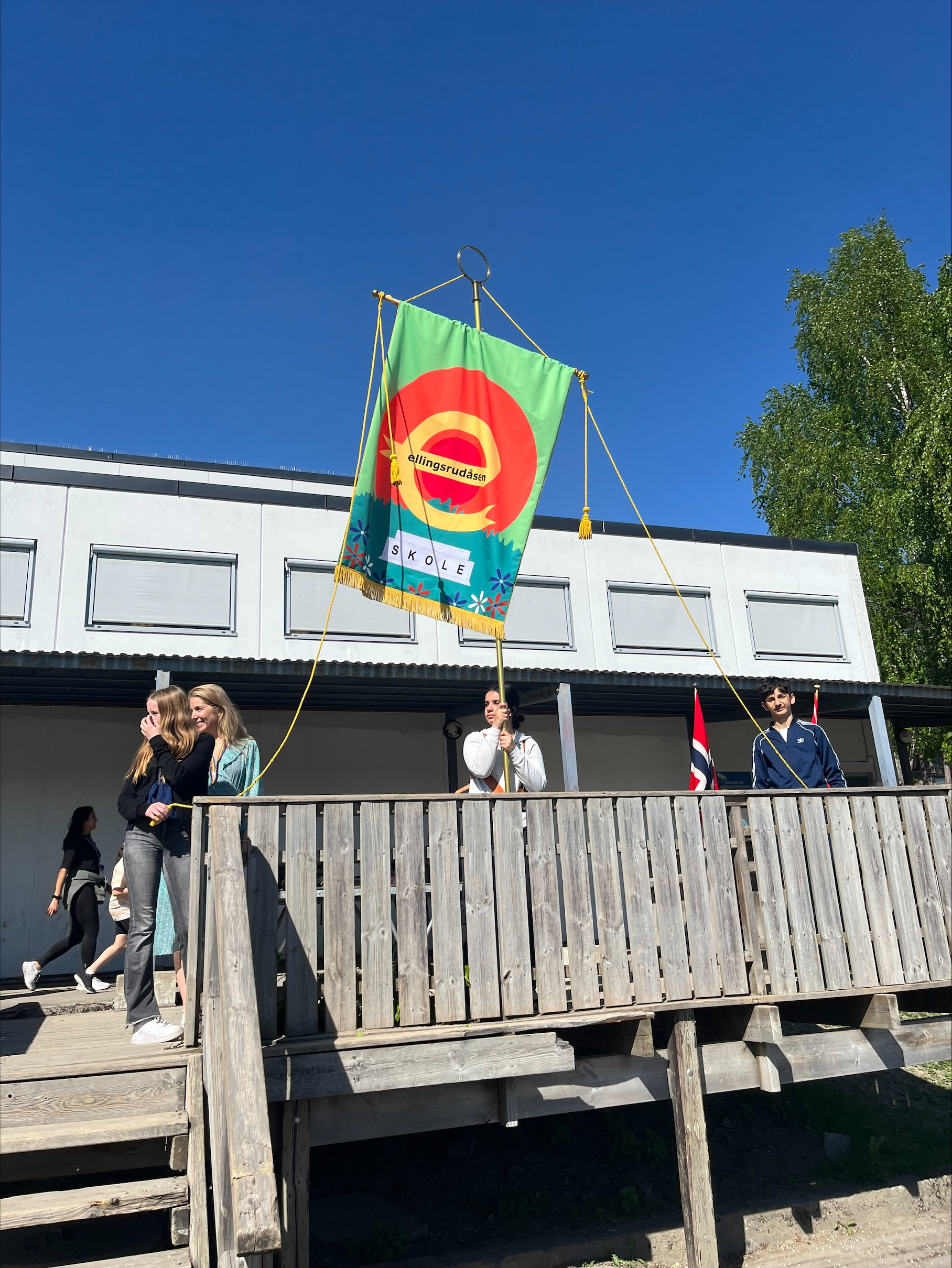 en gruppe mennesker som står utenfor en bygning med et flagg på