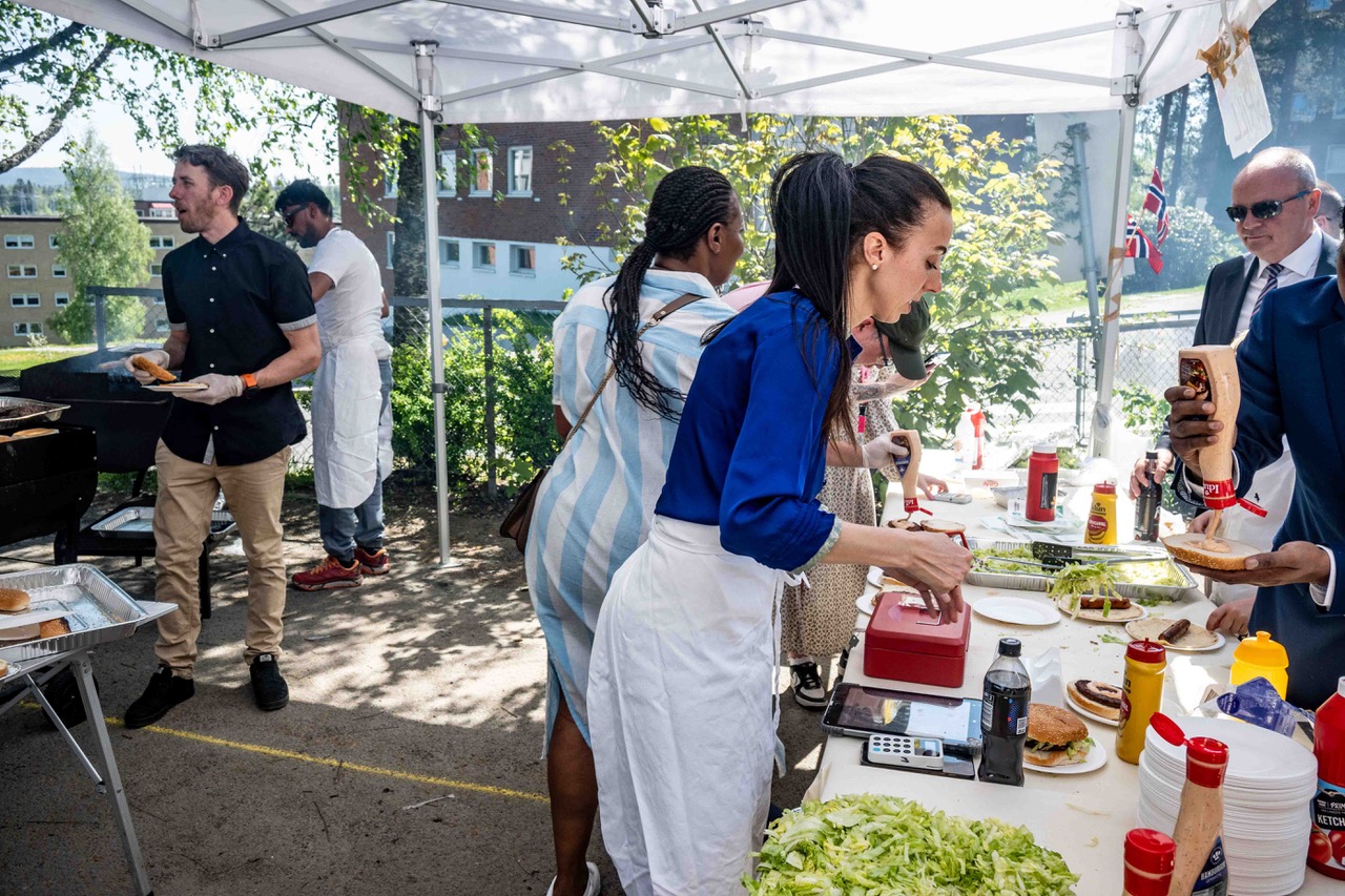 en gruppe mennesker som står rundt et bord med mat på