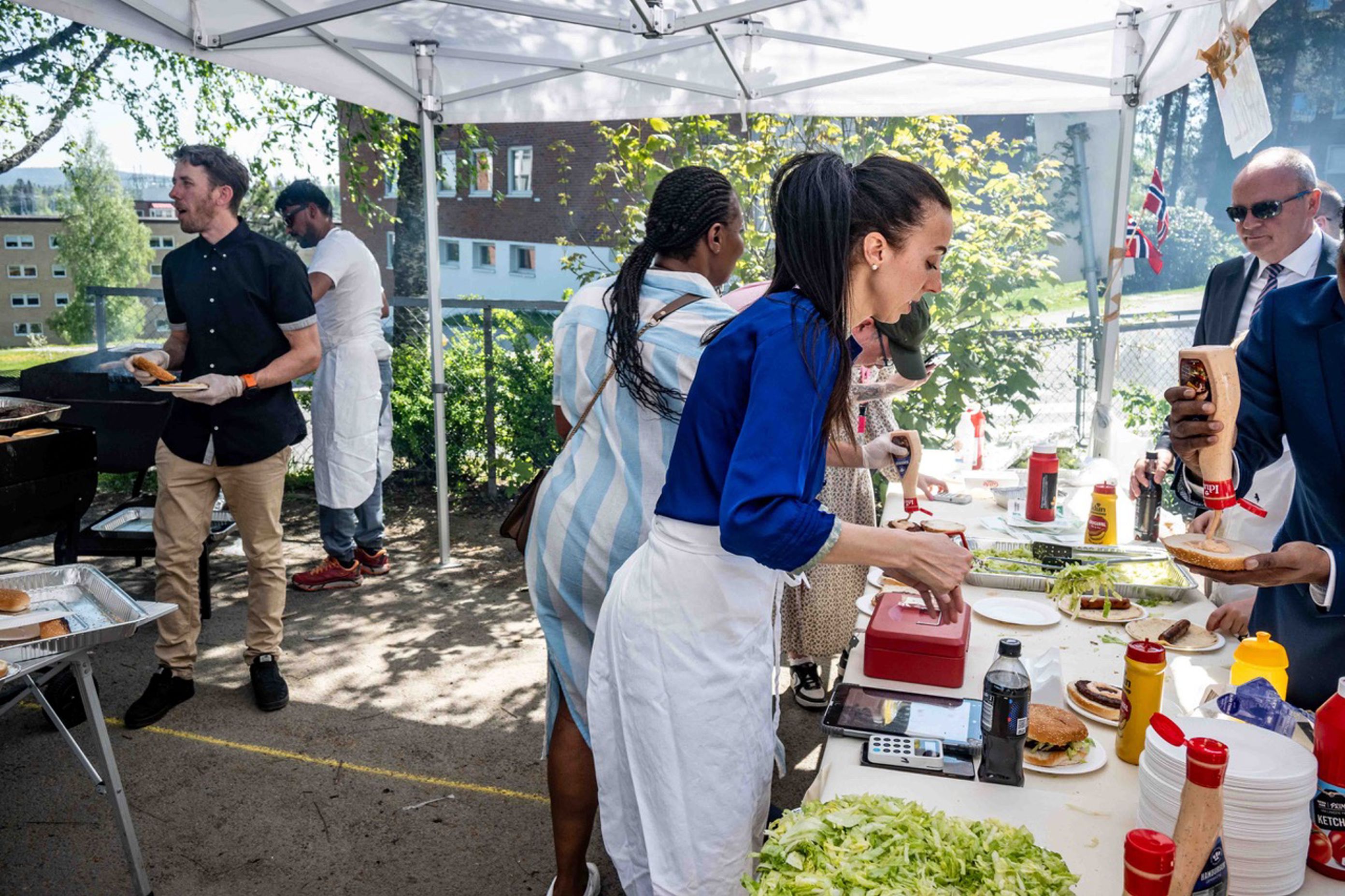 en gruppe mennesker som står rundt et bord med mat på
