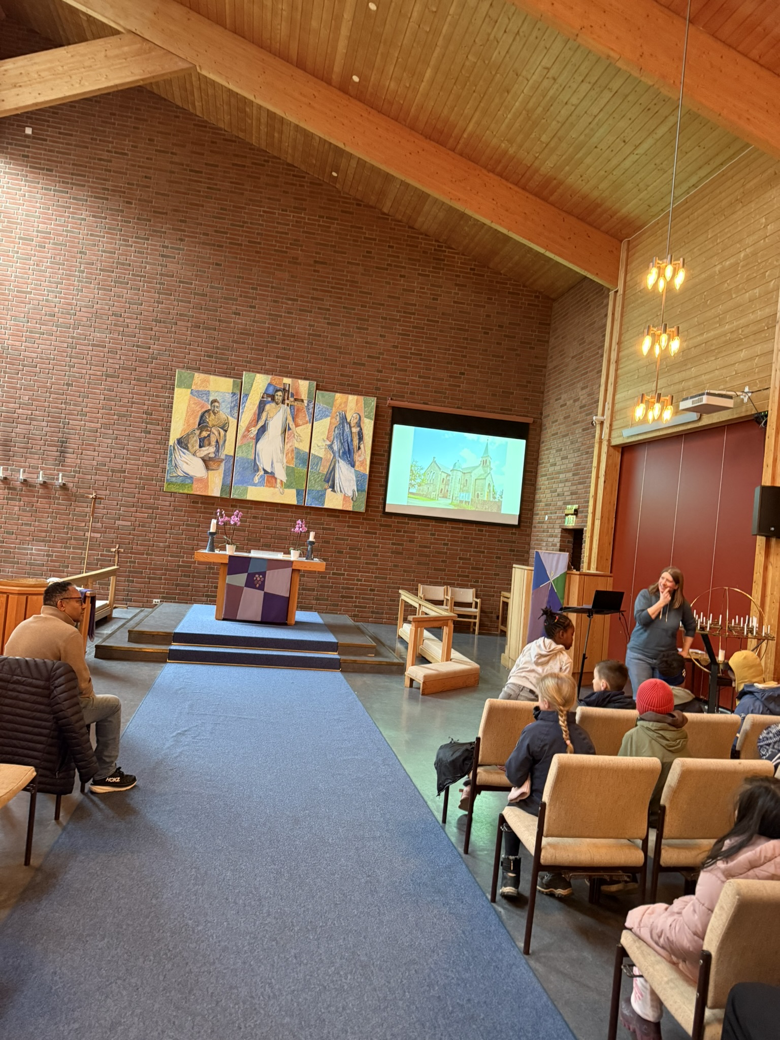 en gruppe mennesker som sitter i et rom med en stor skjerm